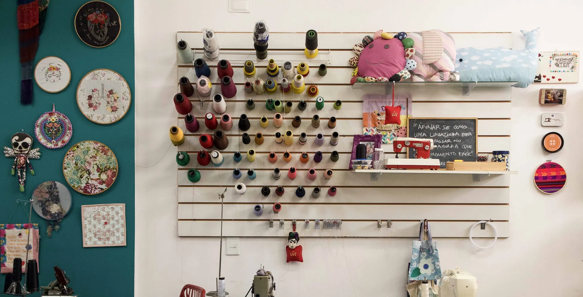 Parede do ateliê com bastidores, tesouras e materiais organizados